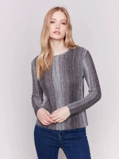 A person with long hair wearing a cozy Space Dye Yarn Crop Sweater by Charlie B and blue jeans stands against a plain background.