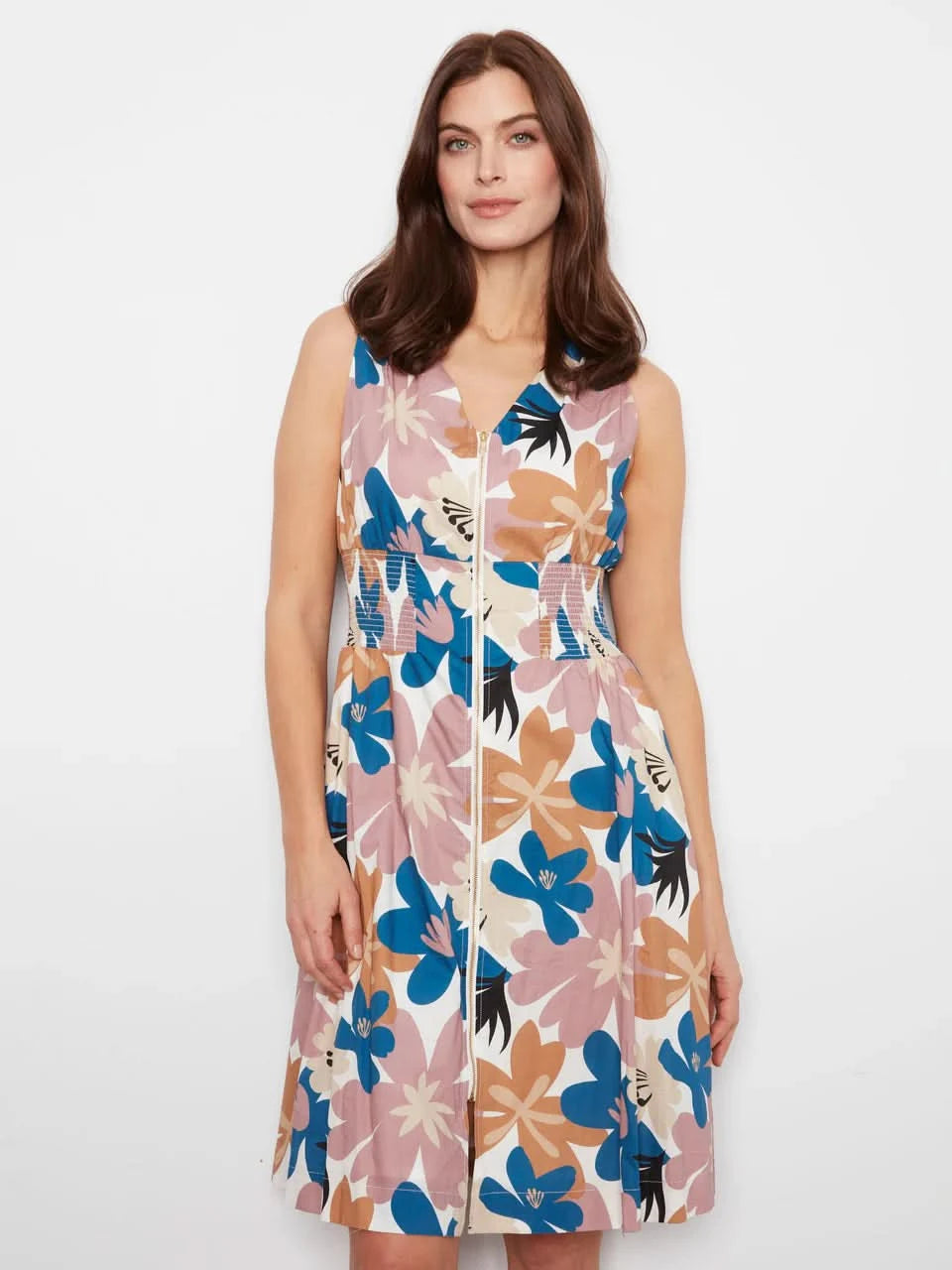 A woman stands against a white wall wearing the Charlie B Cotton Voile Printed Front-Zip Dress and brown sandals.