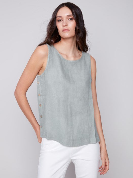 A person in a Charlie B Sleeveless Linen Top with Side Buttons and white pants stands against a plain background.