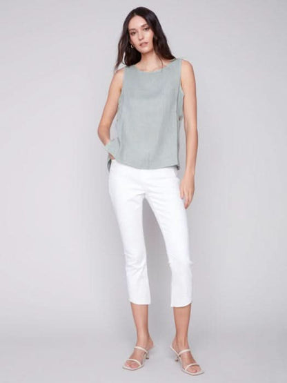 A person in a Charlie B Sleeveless Linen Top with Side Buttons and white pants stands against a plain background.