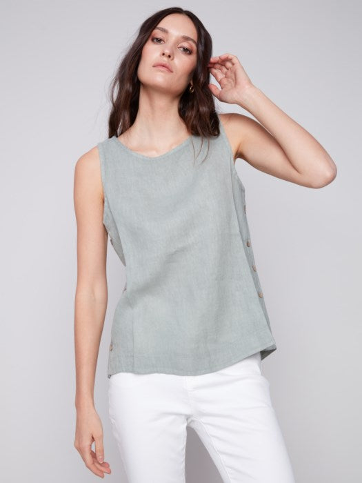 A person in a Charlie B Sleeveless Linen Top with Side Buttons and white pants stands against a plain background.