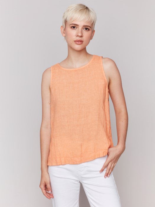 A person in a Charlie B Sleeveless Linen Top with Side Buttons and white pants stands against a plain background.