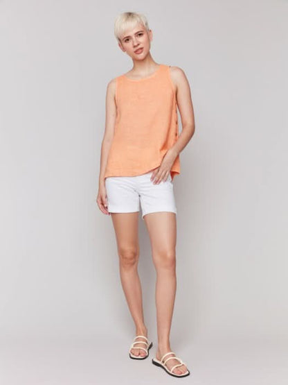A person in a Charlie B Sleeveless Linen Top with Side Buttons and white pants stands against a plain background.