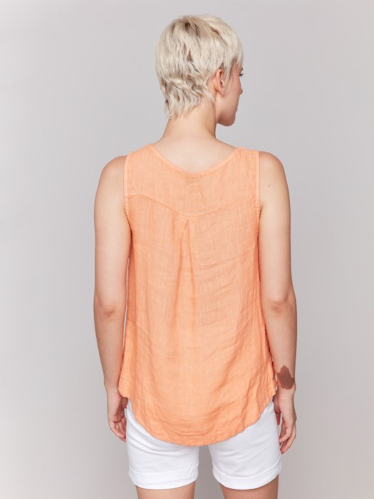 A person in a Charlie B Sleeveless Linen Top with Side Buttons and white pants stands against a plain background.