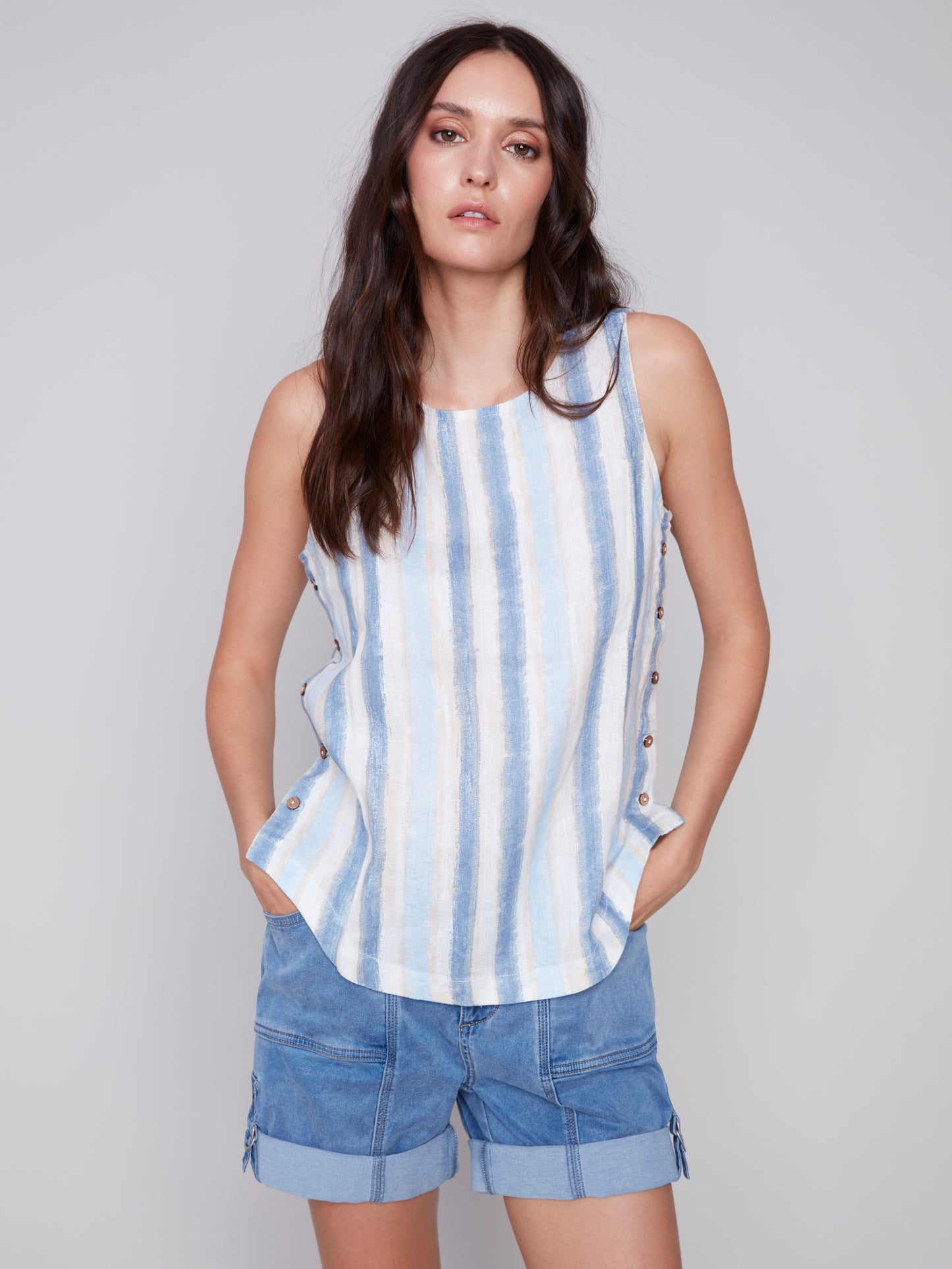 The model is wearing a stylish Charlie B Linen Top with Side Buttons in blue stripes.