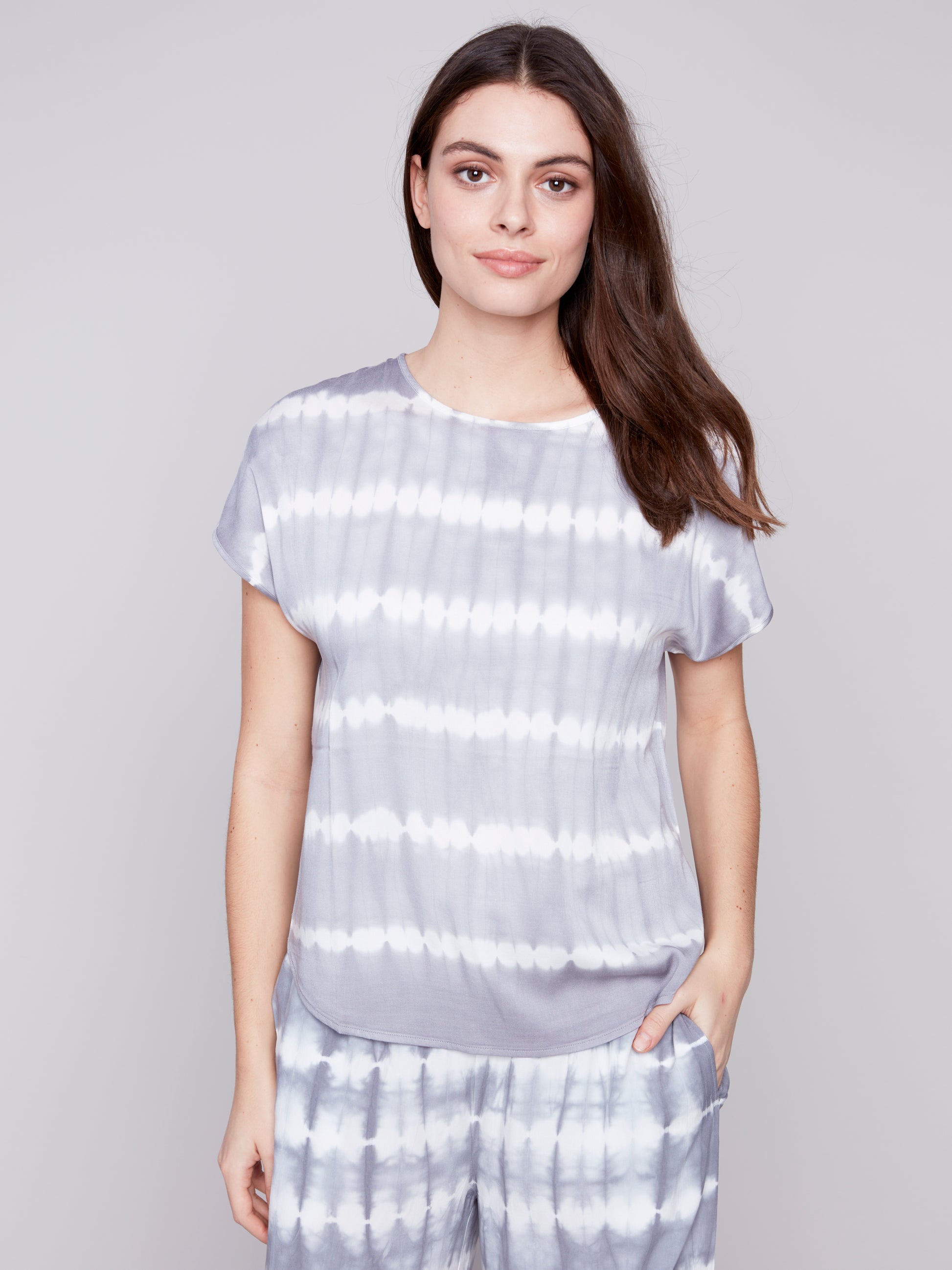 Woman in a Charlie B Tie-Dye Relaxed Top featuring a fun pop of color, posing against a plain background.