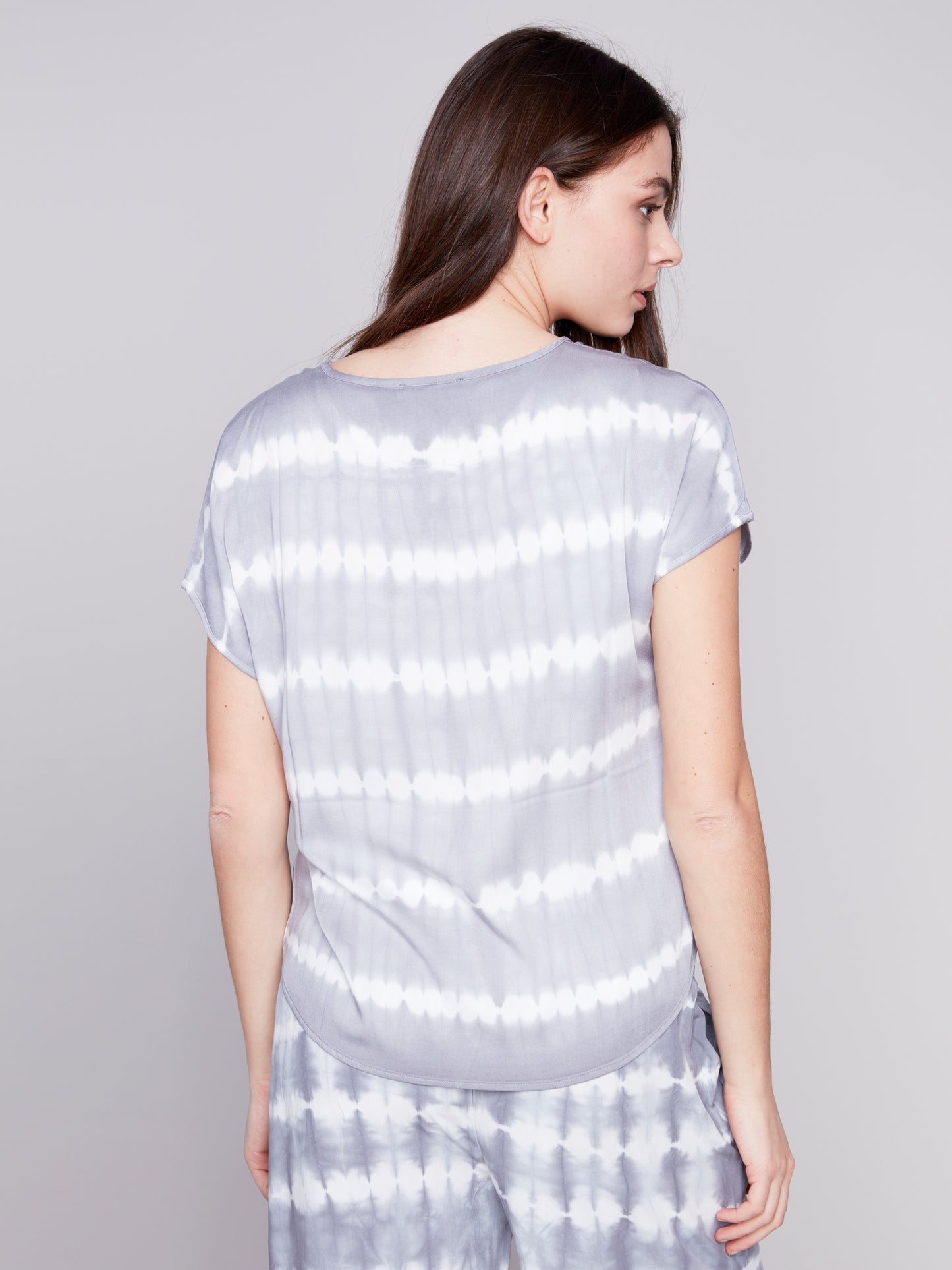 Woman in a Charlie B Tie-Dye Relaxed Top featuring a fun pop of color, posing against a plain background.