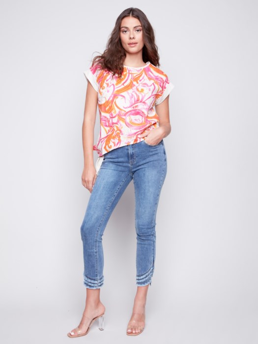 Woman posing in a high-quality Charlie B Printed Linen Knit Combo Top and white pants against a gray background.
