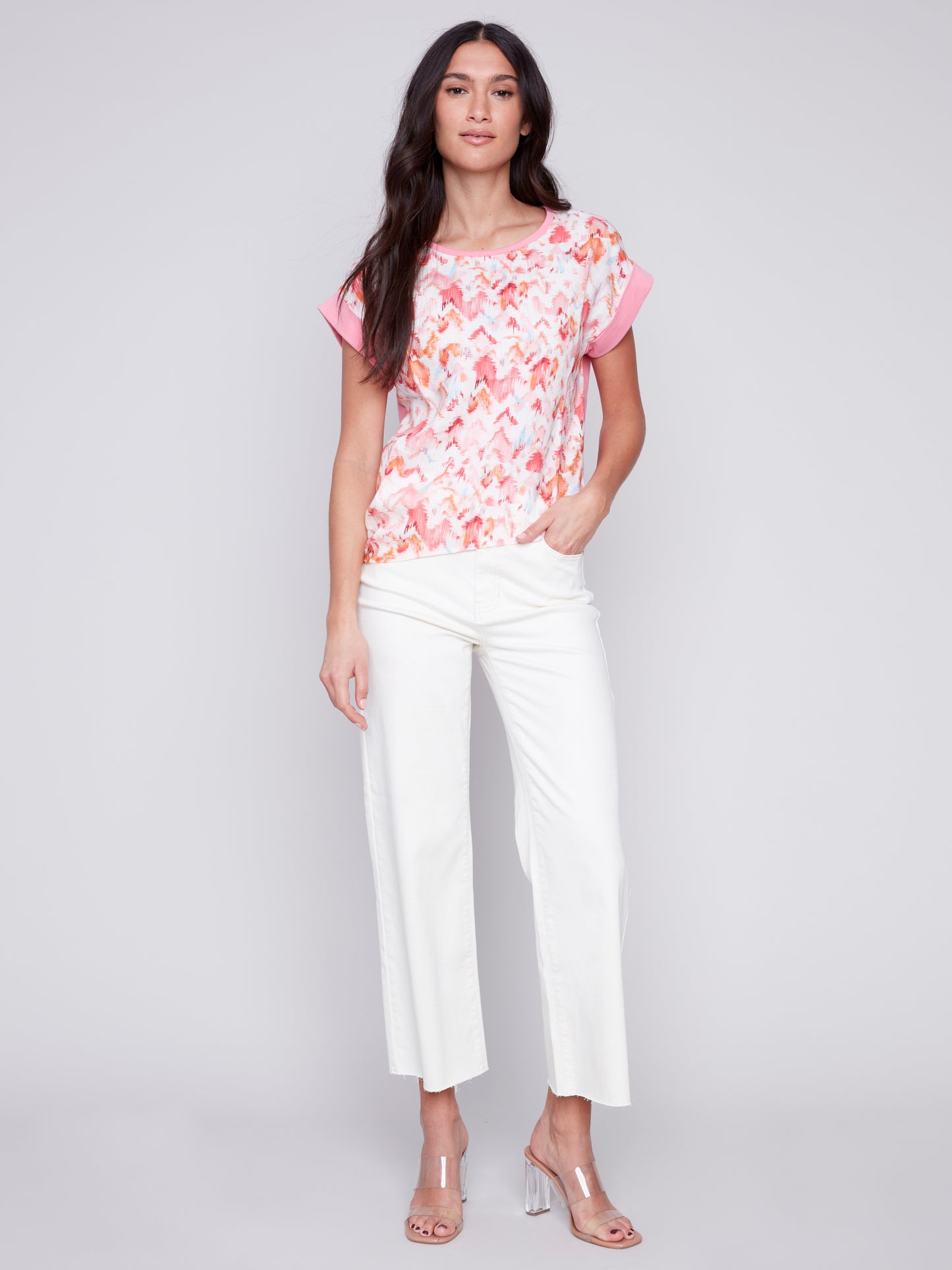 Woman posing in a high-quality Charlie B Printed Linen Knit Combo Top and white pants against a gray background.
