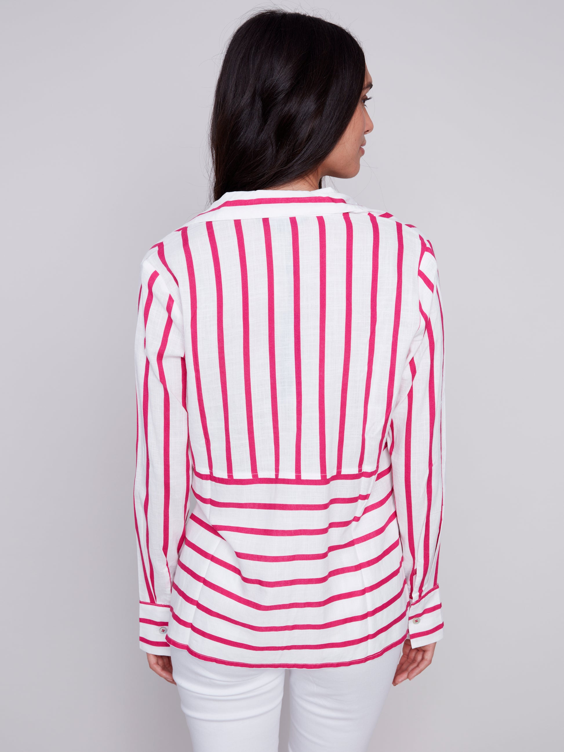 Woman wearing a Charlie B Lined Blend Striped 3/4 Button Top with white pants posing against a gray background.