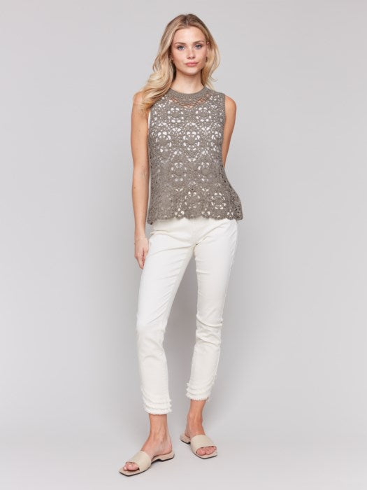 Wearing the Sleeveless Floral Cotton Crochet Top by Charlie B with white pants, the person stands gracefully against a neutral background.