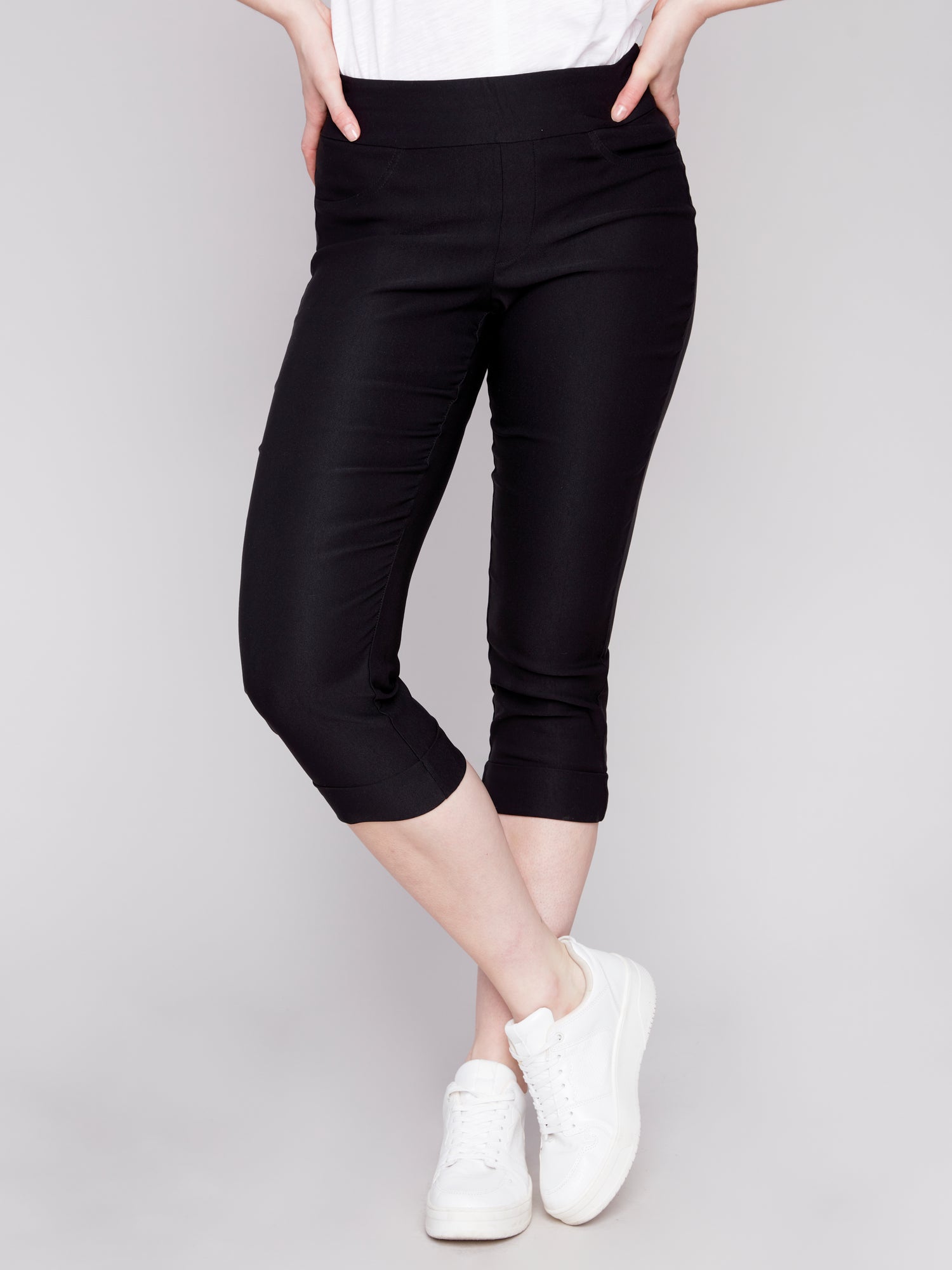 A woman showcasing her stylish Charlie B Stretch Pull-on Capri pants paired with a simple white t-shirt, perfectly balancing style and functionality.