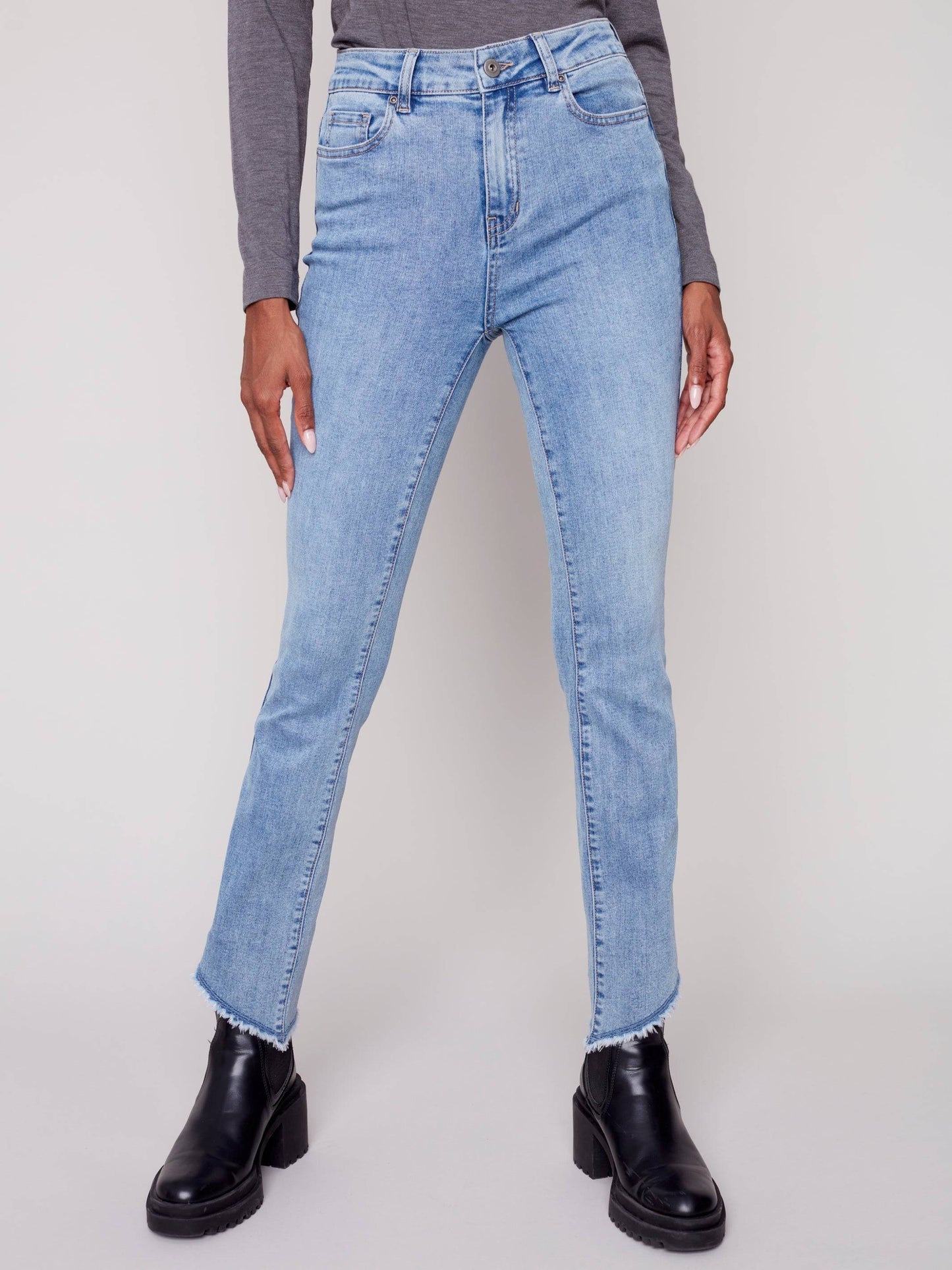 A woman in Charlie B's asymmetrical hem bootcut jeans and black Chelsea boots creates a flattering look.