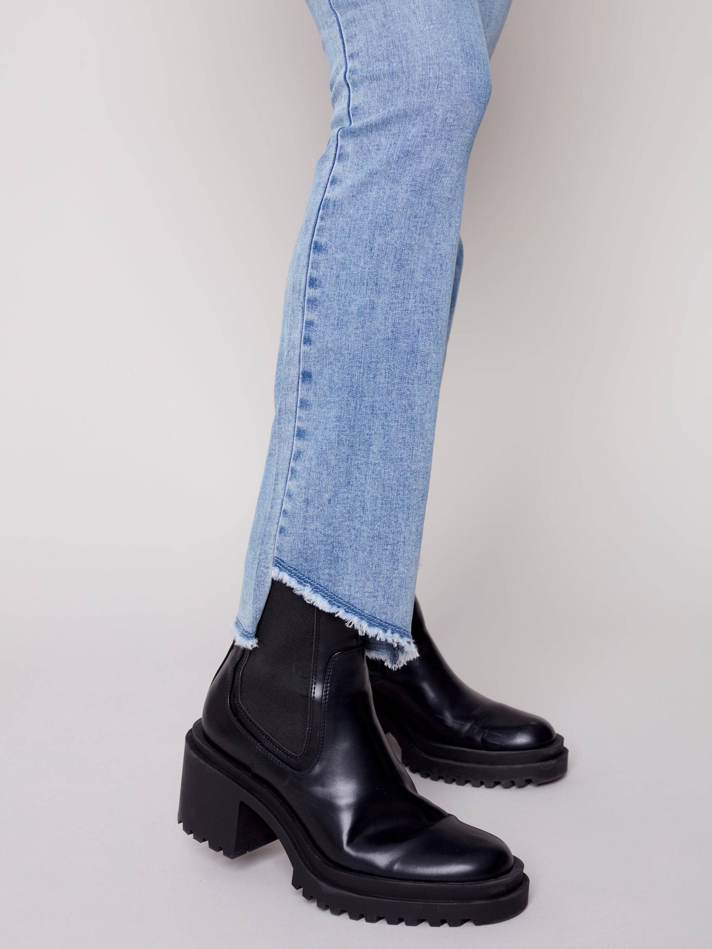 A woman in Charlie B's asymmetrical hem bootcut jeans and black Chelsea boots creates a flattering look.