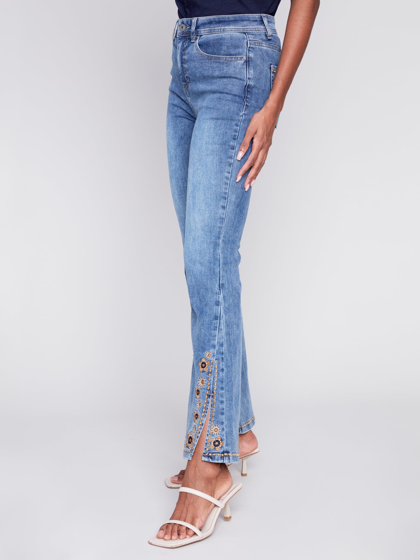 A woman exuding retro vibes in a pair of Charlie B's Slit Bell Bottom Jeans with Embroidered Slits.