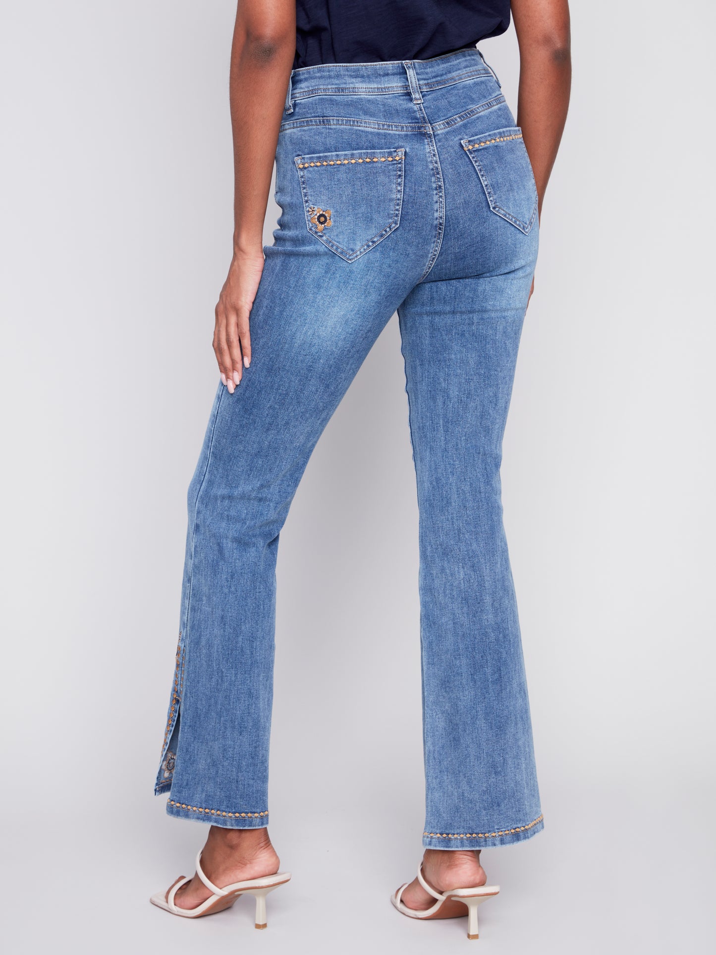 A woman exuding retro vibes in a pair of Charlie B's Slit Bell Bottom Jeans with Embroidered Slits.