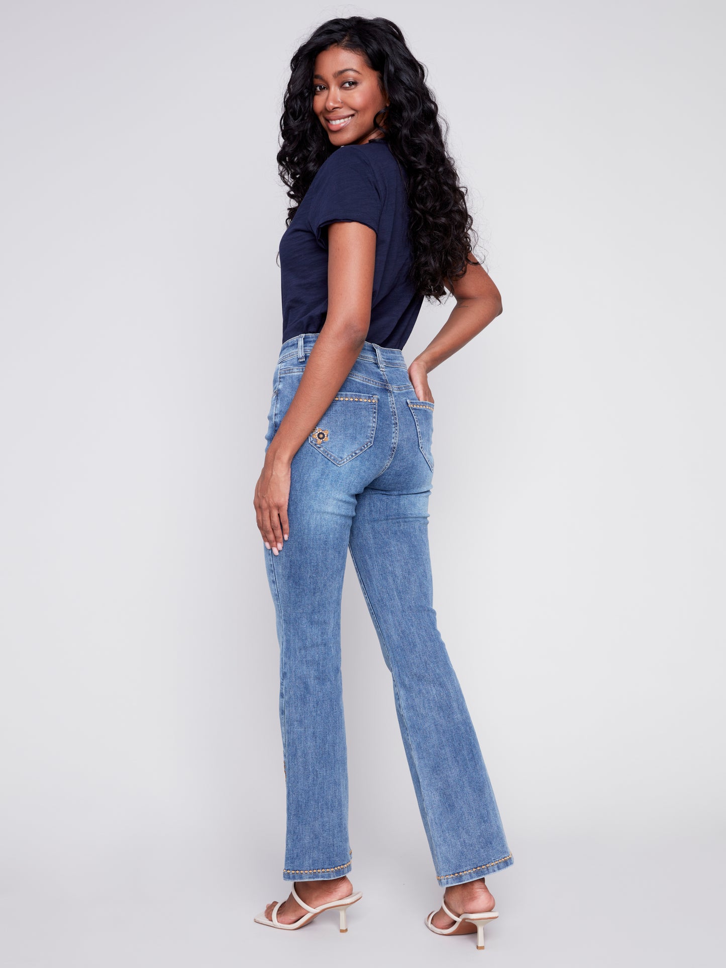 A woman exuding retro vibes in a pair of Charlie B's Slit Bell Bottom Jeans with Embroidered Slits.