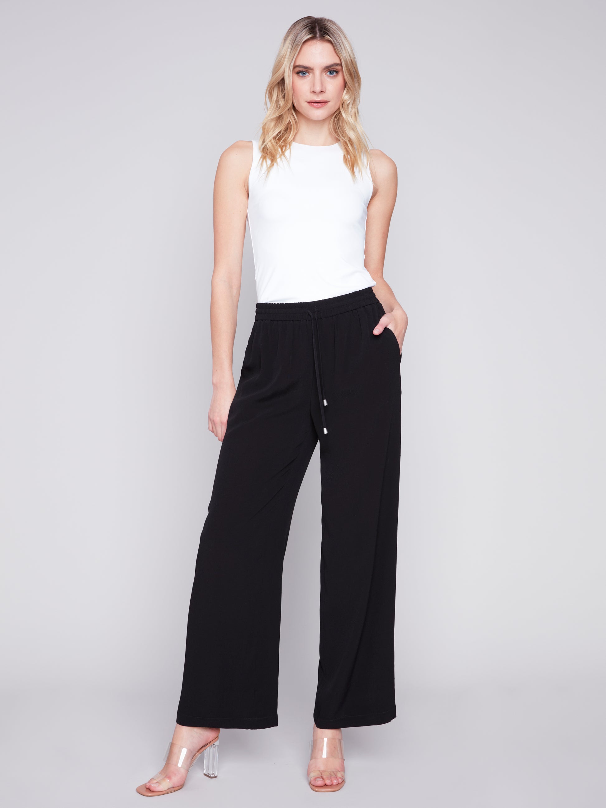 A woman wearing stylish Charlie B black satin wide-leg pants and a white t-shirt.