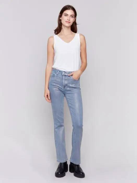 A person wearing Charlie B Foiled Bootcut Jeans and black shoes is facing away from the camera.