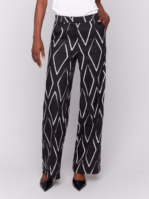 A person in a white t-shirt and Charlie B's Printed Linen-Blend Pants, featuring a chic white geometric design, stands against a gray background.