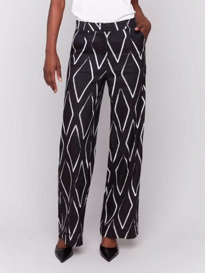 A person in a white t-shirt and Charlie B's Printed Linen-Blend Pants, featuring a chic white geometric design, stands against a gray background.