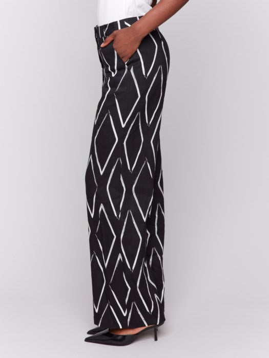 A person in a white t-shirt and Charlie B's Printed Linen-Blend Pants, featuring a chic white geometric design, stands against a gray background.