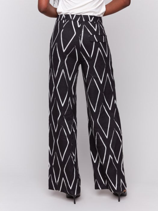 A person in a white t-shirt and Charlie B's Printed Linen-Blend Pants, featuring a chic white geometric design, stands against a gray background.