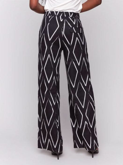 A person in a white t-shirt and Charlie B's Printed Linen-Blend Pants, featuring a chic white geometric design, stands against a gray background.
