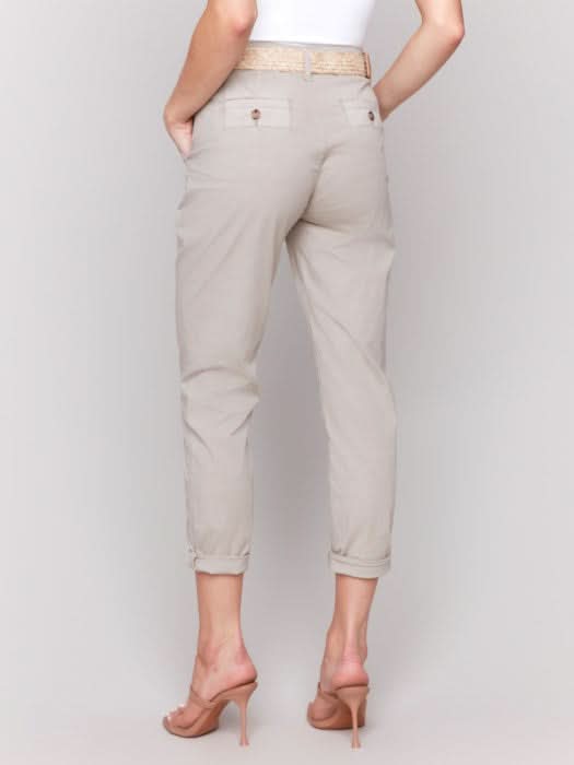 Wearing the essential Slim Pant Leg With Belt by Charlie B, a person in a white sleeveless top stands against a plain gray background, highlighting its flattering fit and slim pant leg that infuse effortless style.