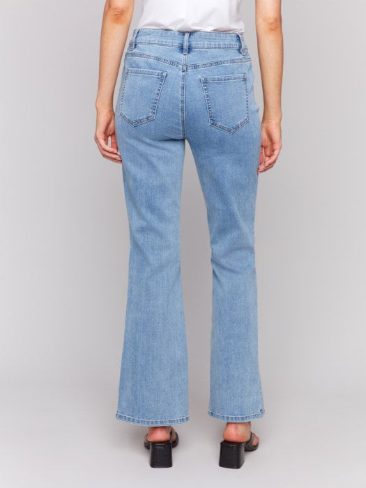 A person is seen from the back wearing Charlie B Floral Embroidered Bootcut Jeans with Front Slits and a white shirt, set against a neutral background.