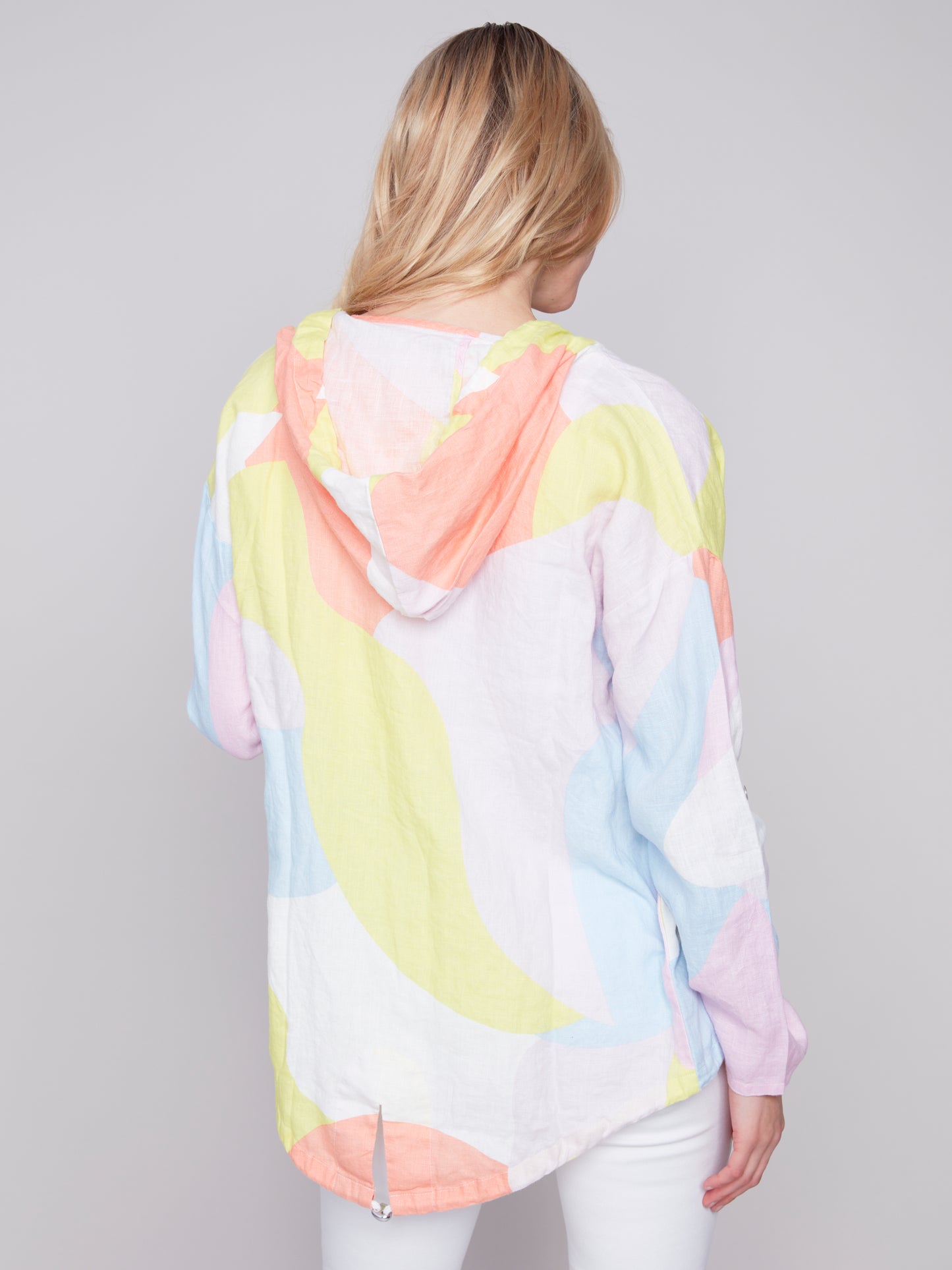Woman wearing a Charlie B Graffiti Duster Jacket and white pants against a grey background.