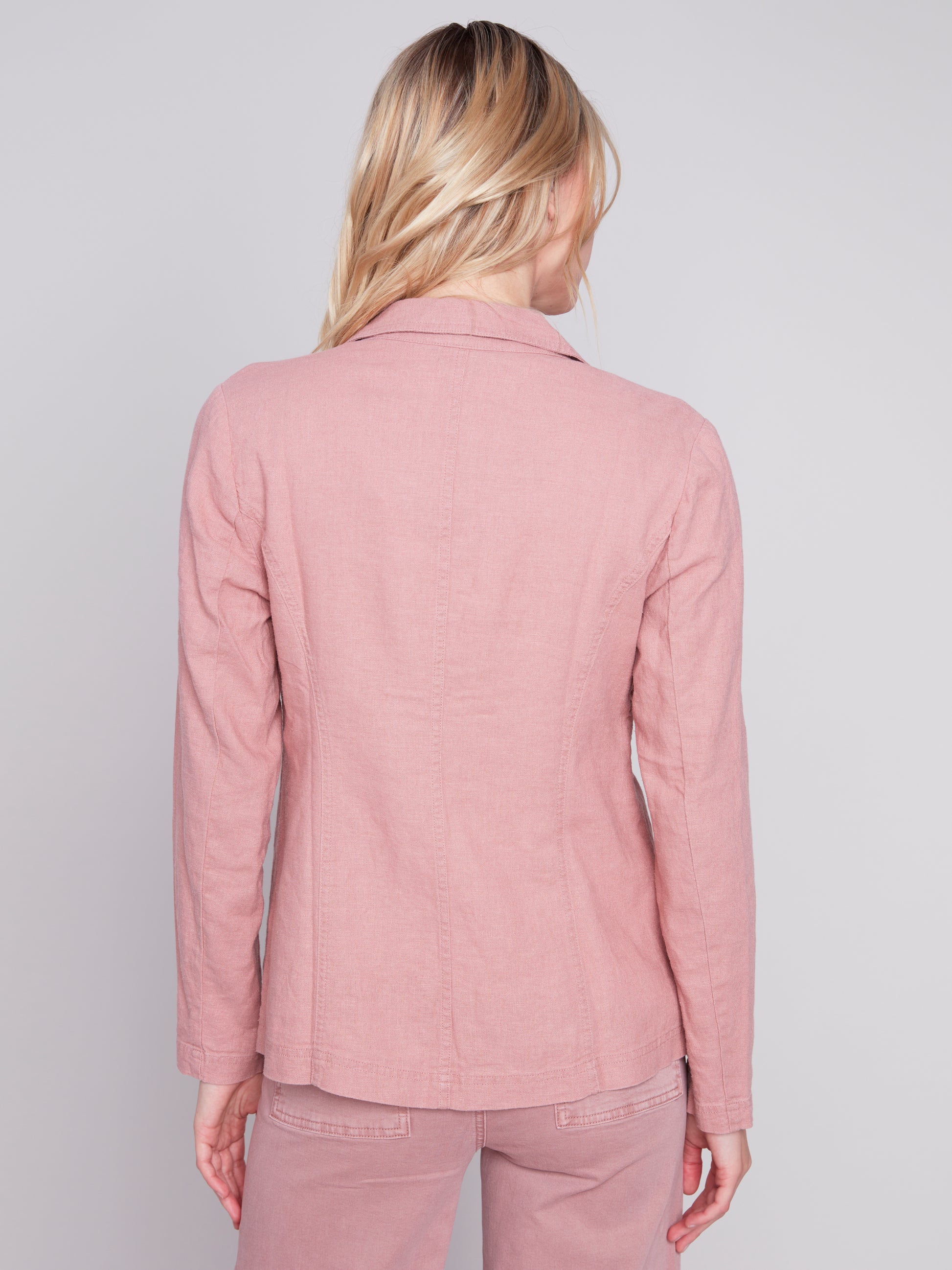 The model is wearing a pink Charlie B lined button-up blazer, a wardrobe staple that is made with high-quality materials.