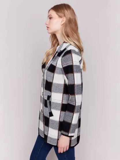 A woman with long hair, standing against a plain background and showcasing her winter wardrobe, is wearing the Charlie B Knit Plaid Coat along with jeans.