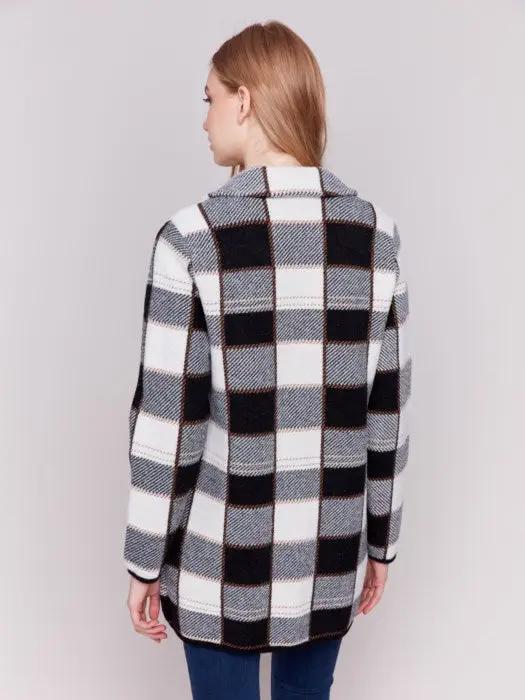 A woman with long hair, standing against a plain background and showcasing her winter wardrobe, is wearing the Charlie B Knit Plaid Coat along with jeans.