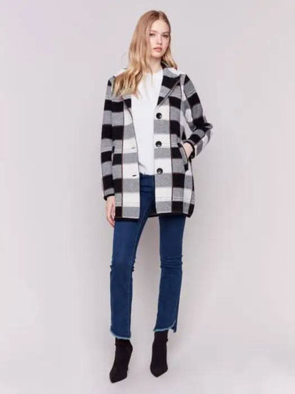 A woman with long hair, standing against a plain background and showcasing her winter wardrobe, is wearing the Charlie B Knit Plaid Coat along with jeans.