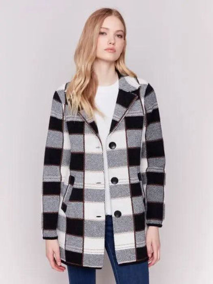 A woman with long hair, standing against a plain background and showcasing her winter wardrobe, is wearing the Charlie B Knit Plaid Coat along with jeans.