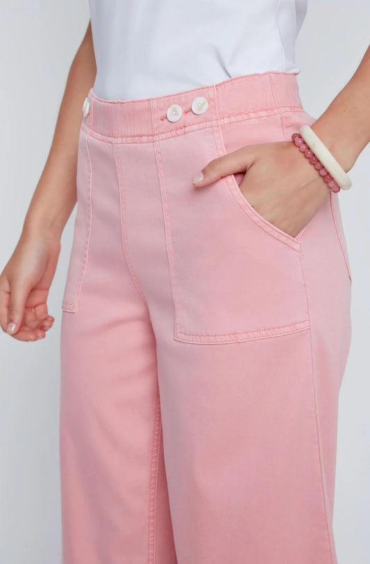 A woman stands against a plain background wearing a white sleeveless top, CoCo Y Club wide-leg cropped pants in light pink Capri Gaucho style, and white sneakers—a perfect addition to any casual wardrobe.