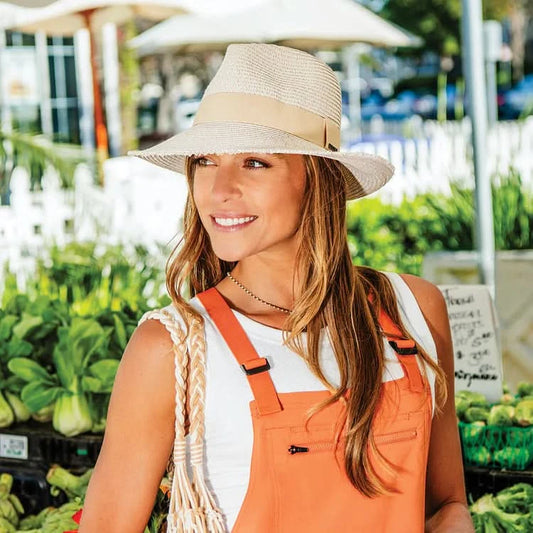 The Wallaroo Carkella Emery Packable Wide Brim is a light tan woven straw cowboy hat with a wide brim and beige hatband, made from lightweight fabric for comfort, shown from a top angle.