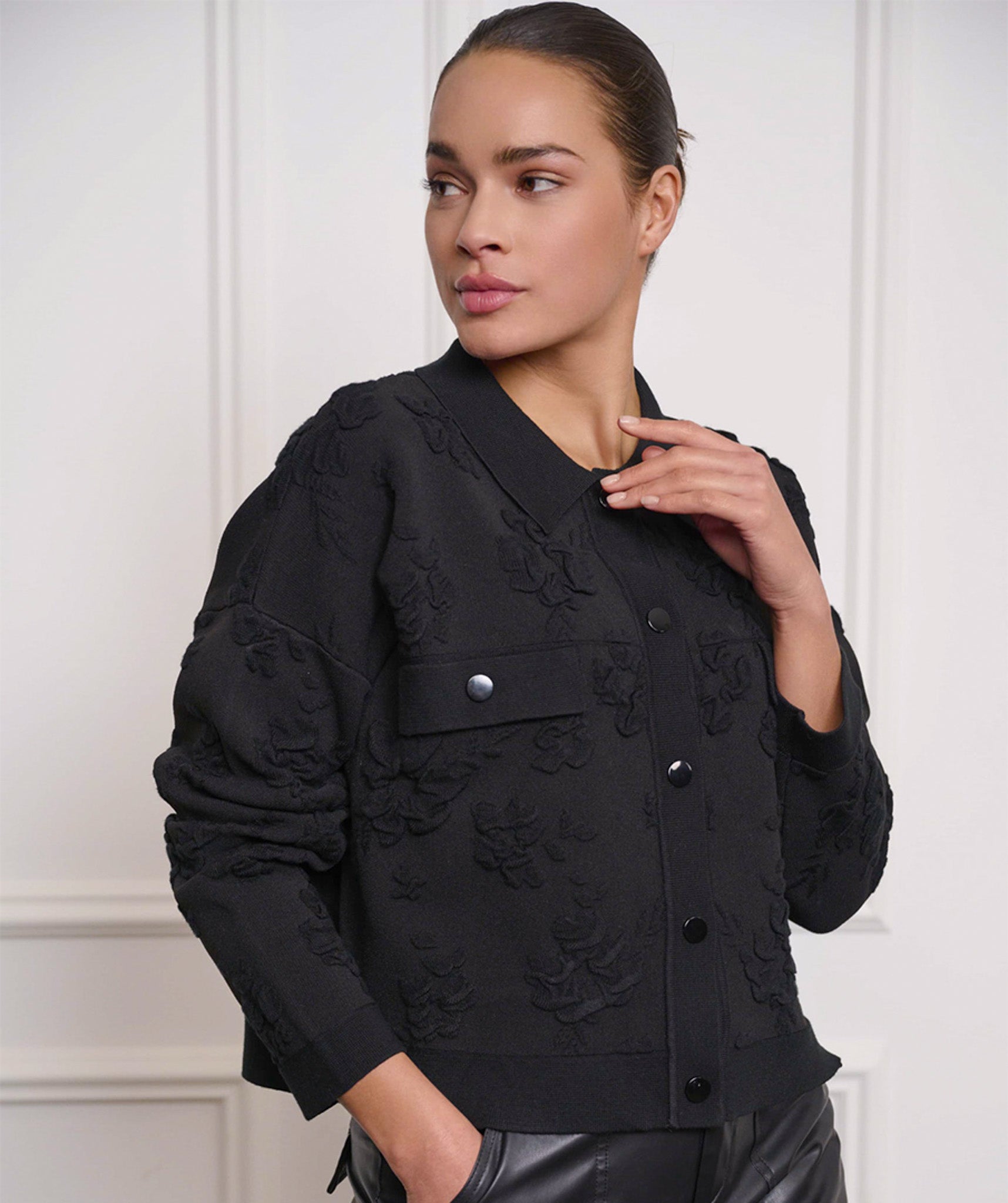 A person wearing Esqualo's Detailed Button Up Jacket in a textured black style with silver buttons, paired with leather pants, stands with one hand in a pocket, gazing to the side.