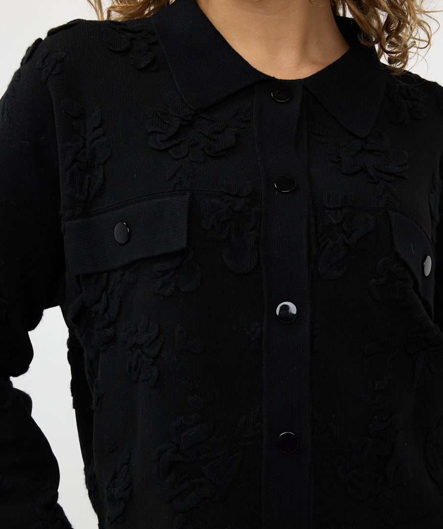 A person wearing Esqualo's Detailed Button Up Jacket in a textured black style with silver buttons, paired with leather pants, stands with one hand in a pocket, gazing to the side.