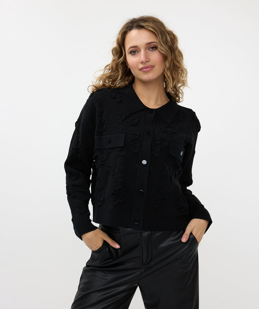 A person wearing Esqualo's Detailed Button Up Jacket in a textured black style with silver buttons, paired with leather pants, stands with one hand in a pocket, gazing to the side.