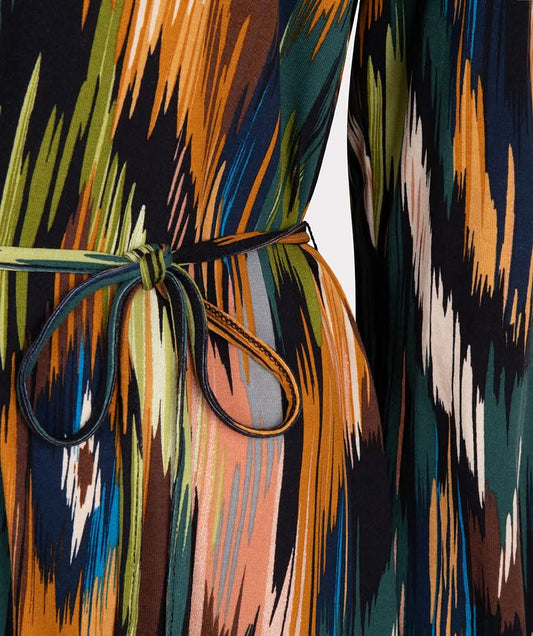 Wearing the versatile and stylish V-Neck Amazon Dress by Esqualo, this person pairs the vibrant, multicolored patterned garment with classic brown boots against a clean white background.
