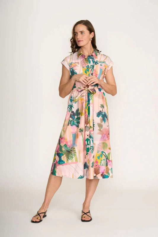 A woman wears the Foil Atrium Dress—a light pink, short-sleeve midi dress with a vibrant tropical print—against a plain white background.