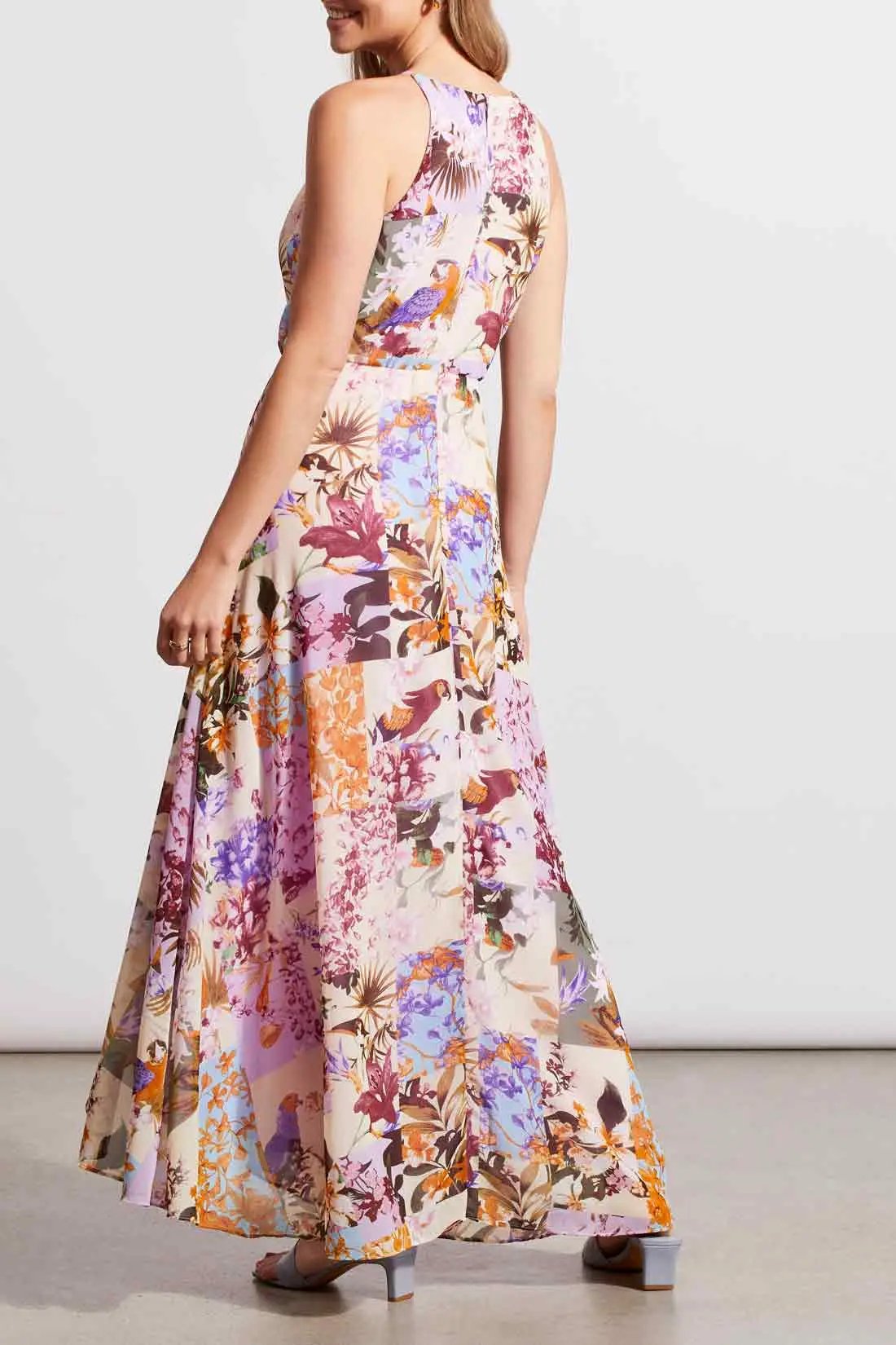 A woman wearing a flowing, floral Tribal maxi dress with halter neckline, posing in a studio setting.
