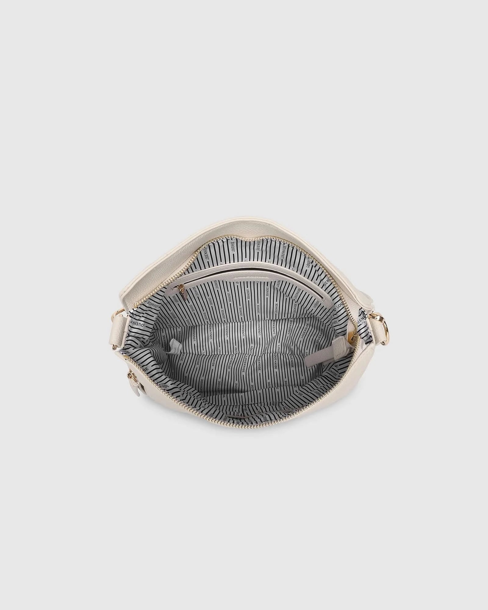 The Louenhide NADIA SHOULDER BAG is cream-colored, crafted from vegan leather with a single shoulder strap, gold-tone hardware, and a side zipper tassel, shown on a plain light background.