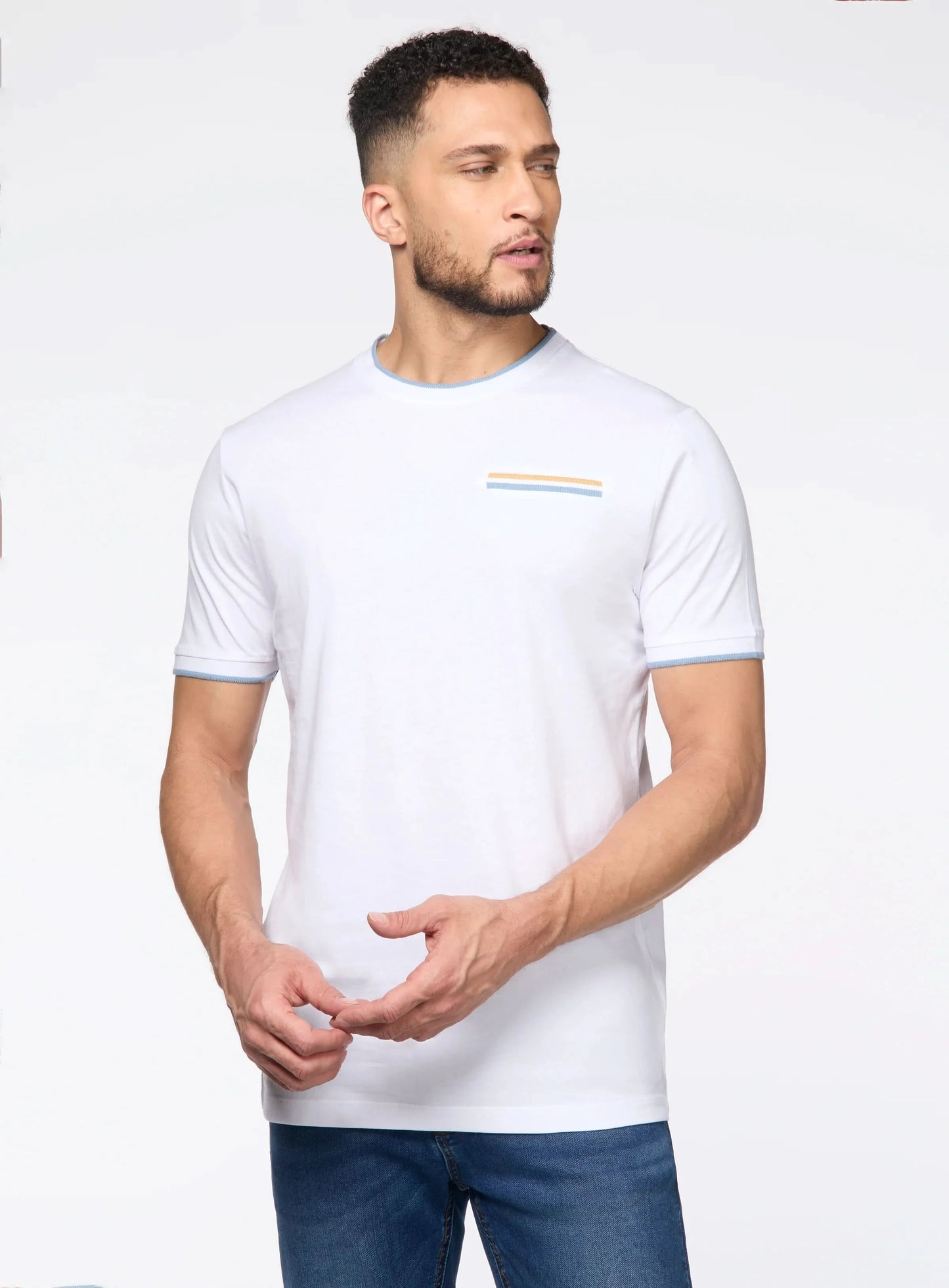 A man wears the Point Zero Mens Crewneck T-shirt—a modern minimalist white tee with light blue trim and a small striped chest accent—showcasing premium casual style.