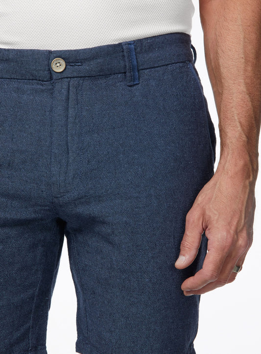 Close-up of a person wearing Point Zero Mens Chino Linen Flat Front Shorts in blue and a white textured shirt, with their right hand by their side—showcasing an effortless summer look in breathable fabric.