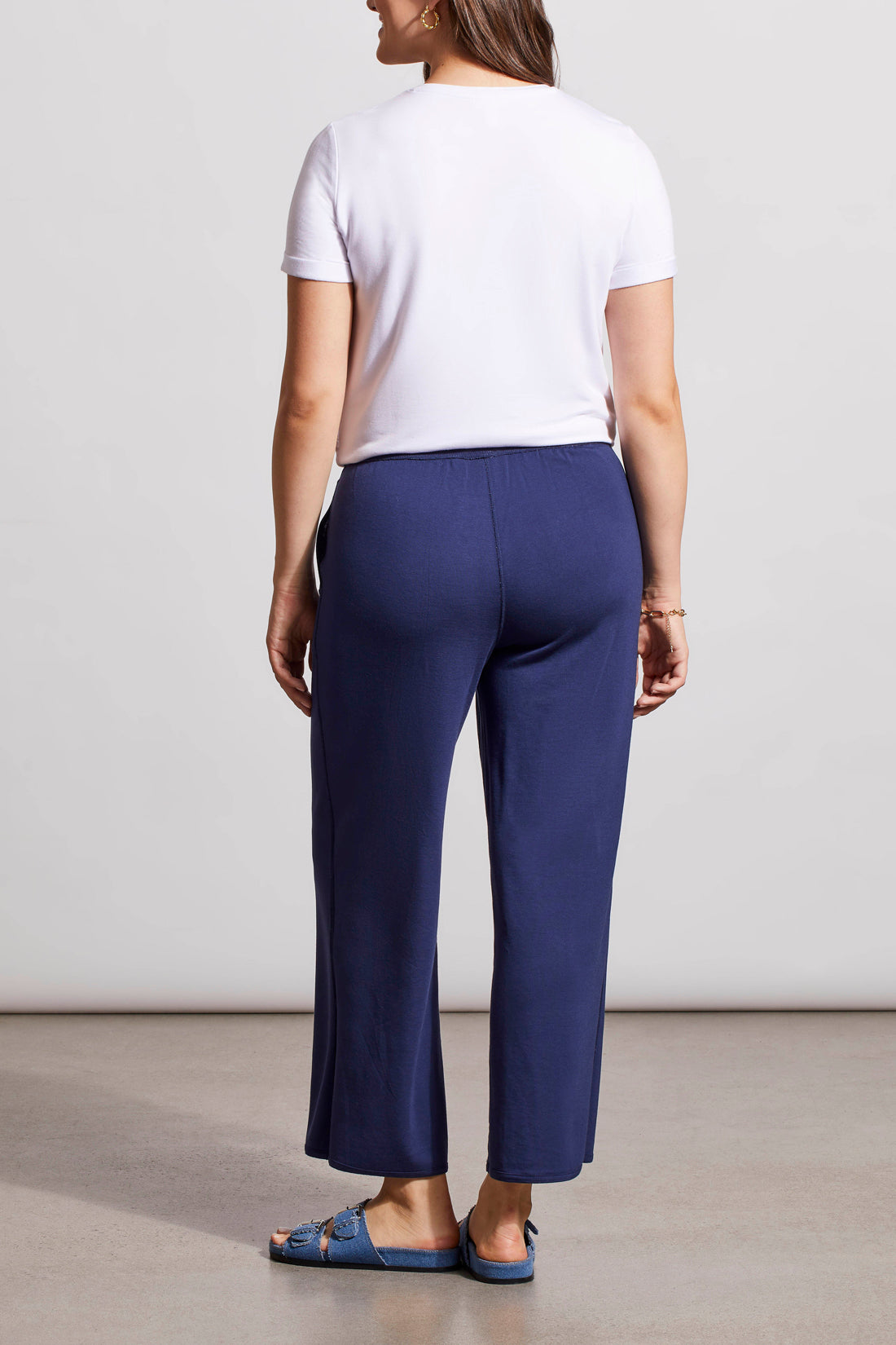 Woman wearing a white knot-front t-shirt and Tribal's blue patterned Reversible Crop Wide Leg Pants with matching slide sandals.