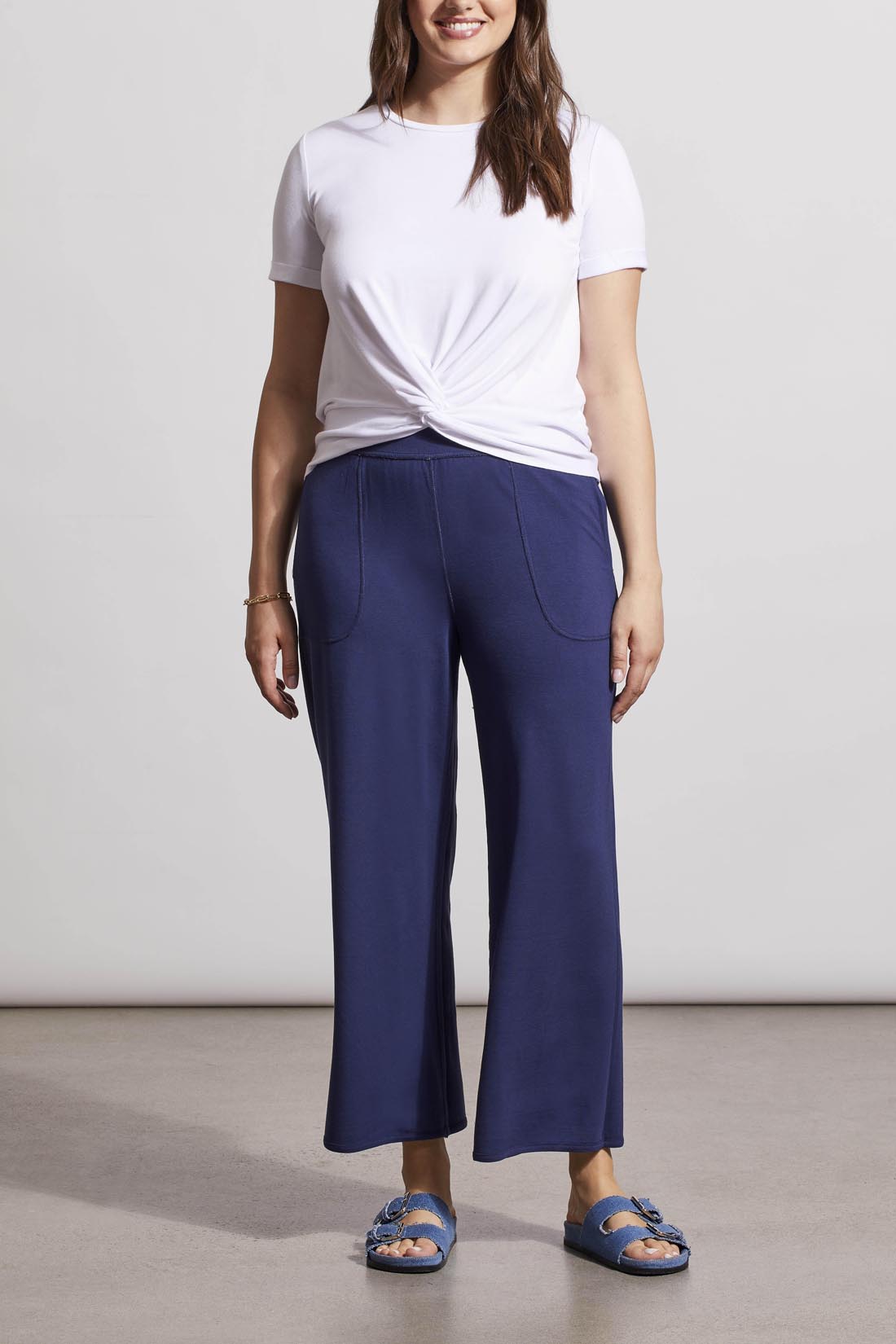 Woman wearing a white knot-front t-shirt and Tribal's blue patterned Reversible Crop Wide Leg Pants with matching slide sandals.