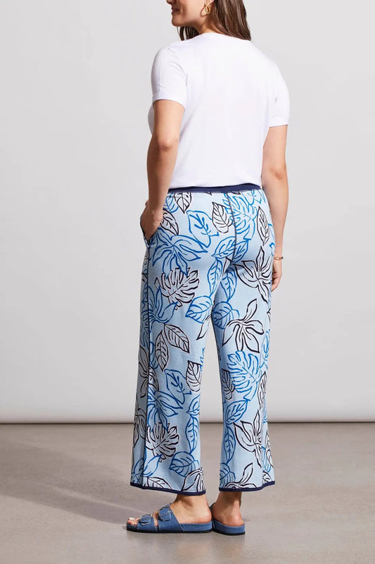 Woman wearing a white knot-front t-shirt and Tribal's blue patterned Reversible Crop Wide Leg Pants with matching slide sandals.